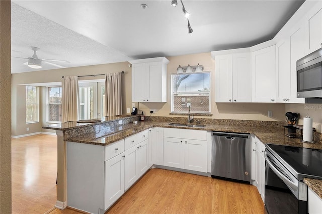 kitchen with white cabinetry, kitchen peninsula, appliances with stainless steel finishes, and sink