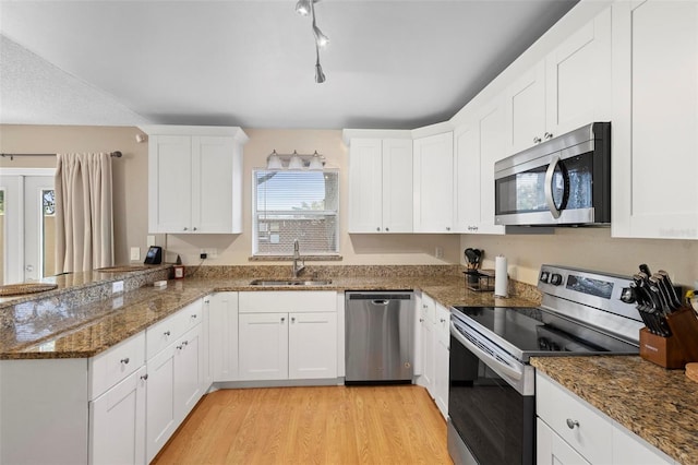 kitchen featuring stainless steel appliances, white cabinetry, sink, dark stone counters, and light hardwood / wood-style flooring