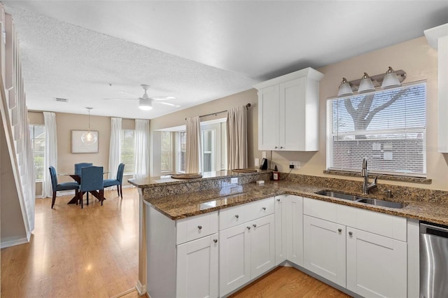 kitchen with white cabinets, stainless steel dishwasher, a textured ceiling, and sink