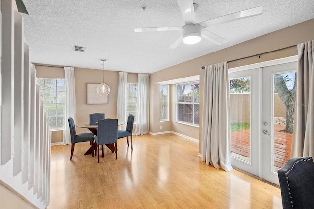 dining area with light hardwood / wood-style floors, a healthy amount of sunlight, and french doors