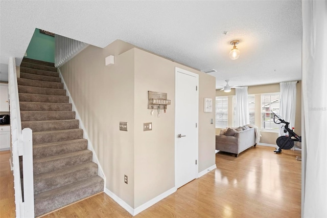 staircase featuring hardwood / wood-style floors, a textured ceiling, and ceiling fan