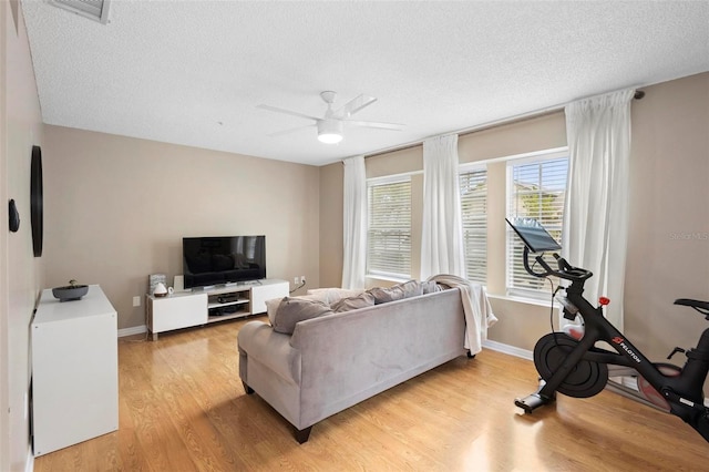 living room featuring a textured ceiling, ceiling fan, and light hardwood / wood-style flooring