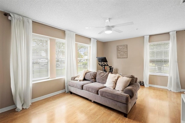 living room with light hardwood / wood-style floors, ceiling fan, and a textured ceiling