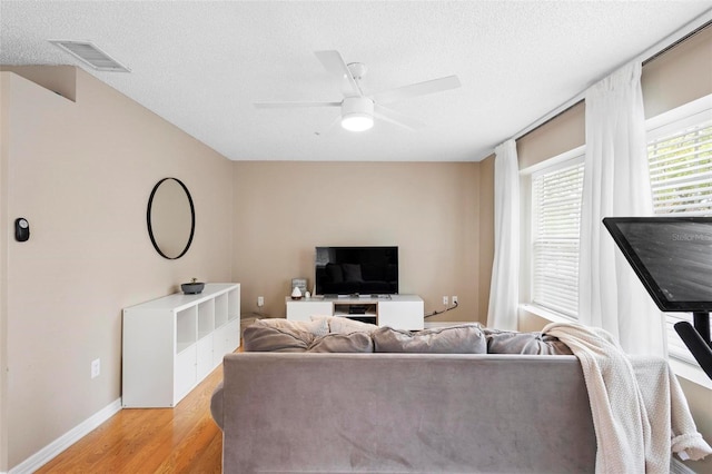 living room featuring a textured ceiling, light wood-type flooring, and ceiling fan