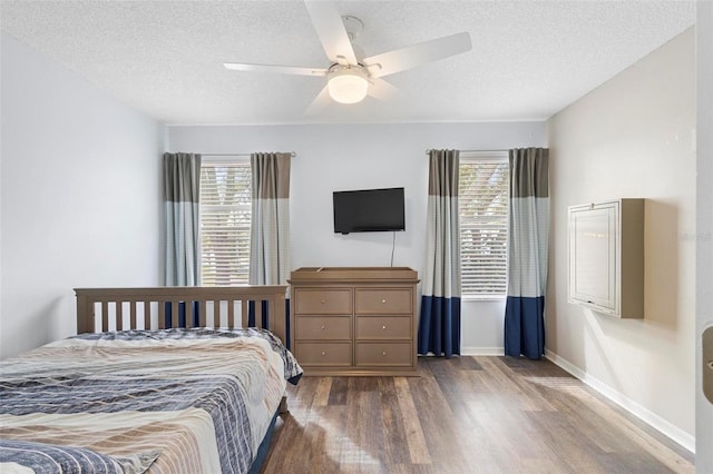 bedroom featuring dark wood-type flooring, ceiling fan, multiple windows, and a textured ceiling