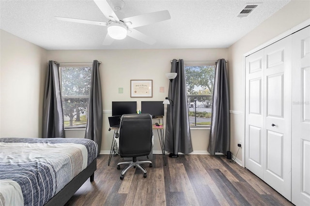 bedroom with a textured ceiling, ceiling fan, dark hardwood / wood-style floors, and a closet