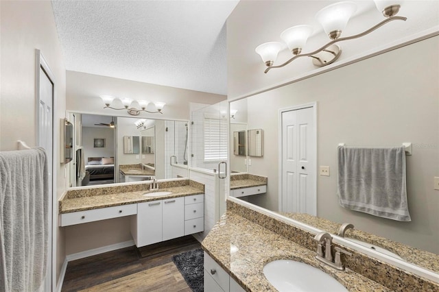 bathroom featuring vanity, a textured ceiling, a shower with door, and wood-type flooring