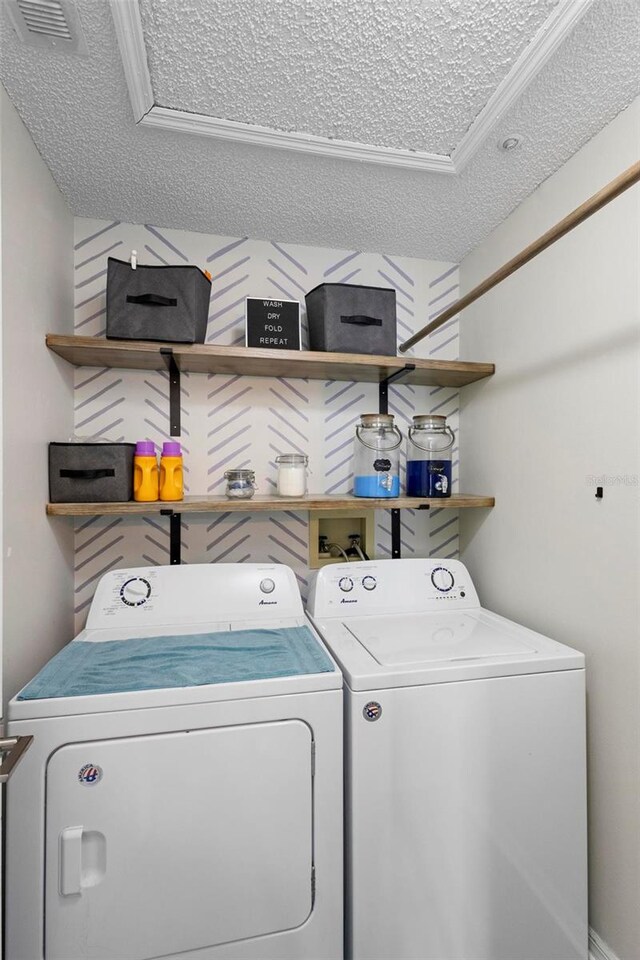 laundry room featuring ornamental molding, washing machine and dryer, and a textured ceiling