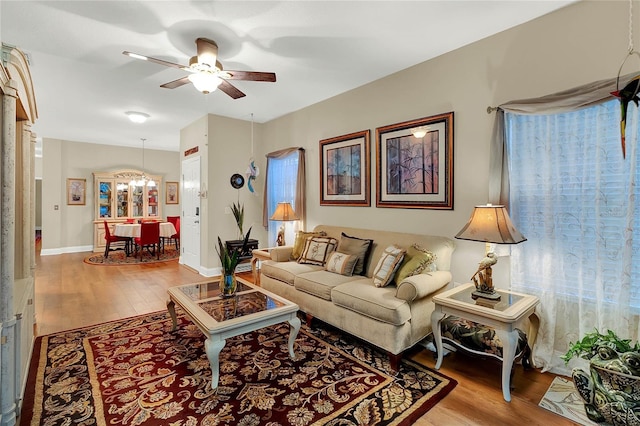 living room with light hardwood / wood-style floors and ceiling fan with notable chandelier