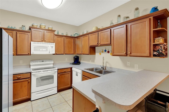 kitchen with white appliances, a breakfast bar area, sink, and kitchen peninsula