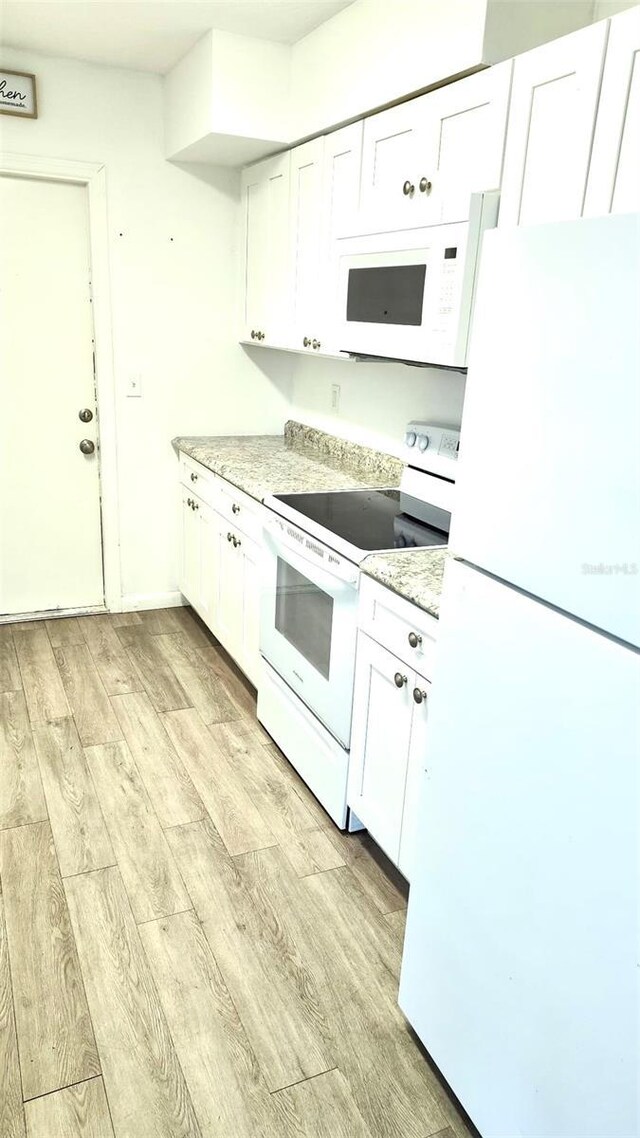 kitchen featuring light stone countertops, white cabinets, white appliances, and light hardwood / wood-style floors