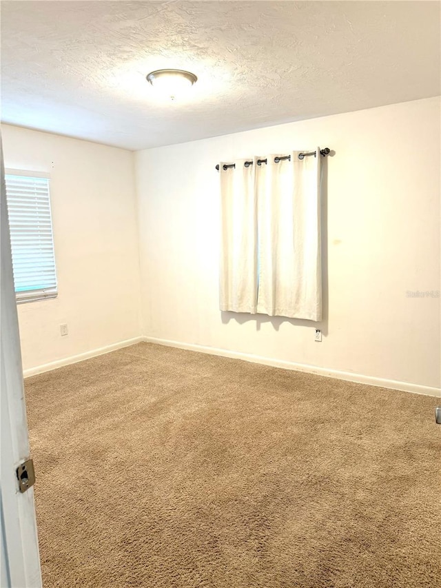 carpeted empty room with a textured ceiling