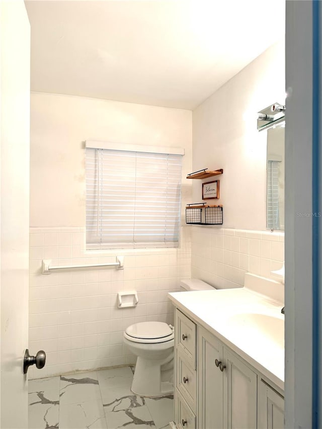 bathroom with vanity, toilet, and tile walls