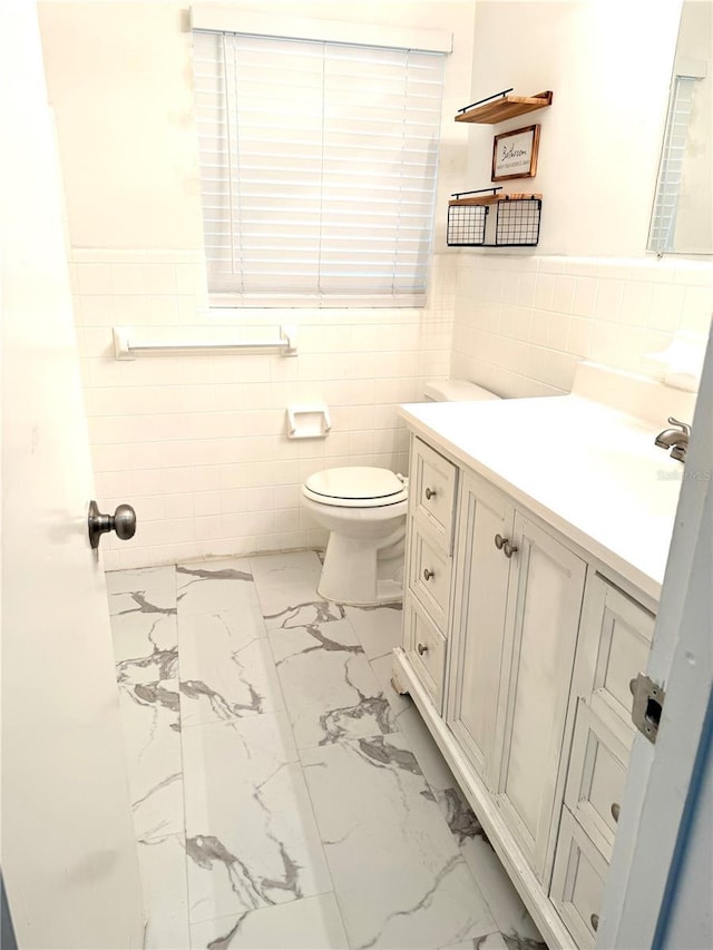 bathroom featuring vanity, tile walls, and toilet