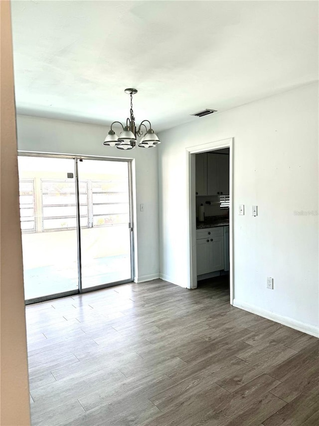 unfurnished room featuring hardwood / wood-style floors and a notable chandelier