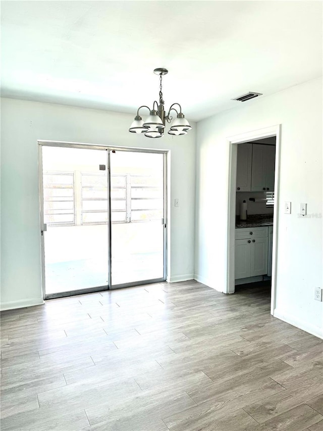 unfurnished dining area with an inviting chandelier and light hardwood / wood-style flooring