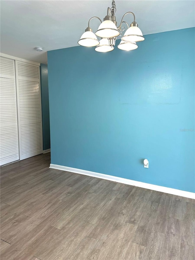 empty room with hardwood / wood-style floors and a chandelier