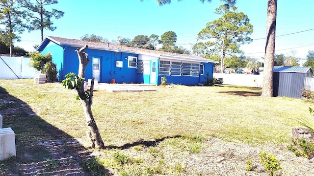 back of house with a storage shed and a yard