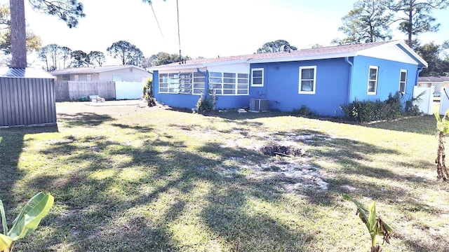 rear view of house featuring cooling unit and a lawn