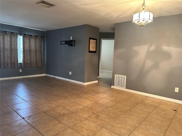 spare room featuring a textured ceiling and an inviting chandelier