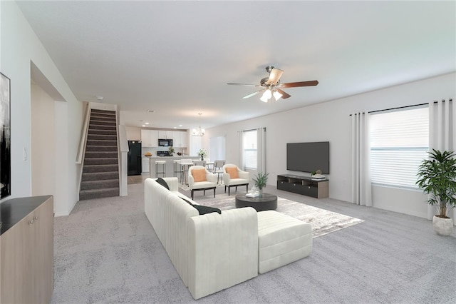 living room with ceiling fan, plenty of natural light, and light carpet