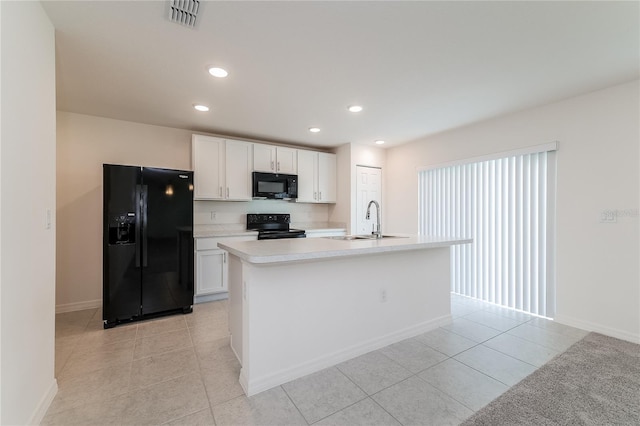 kitchen featuring black appliances, sink, light tile patterned floors, a kitchen island with sink, and white cabinetry