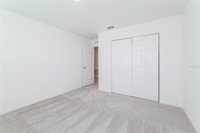 unfurnished bedroom with a closet and light colored carpet