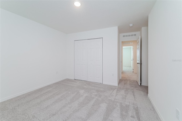 unfurnished bedroom with light colored carpet and a closet