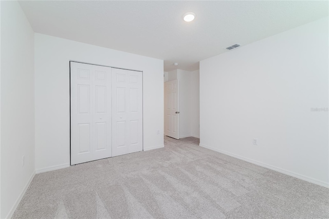 unfurnished bedroom with a closet and light colored carpet