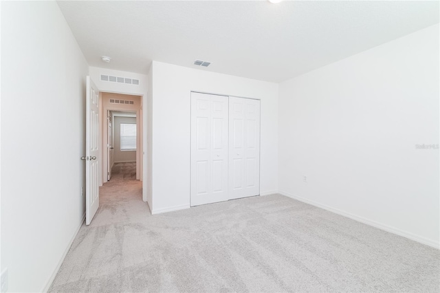 unfurnished bedroom with light colored carpet and a closet