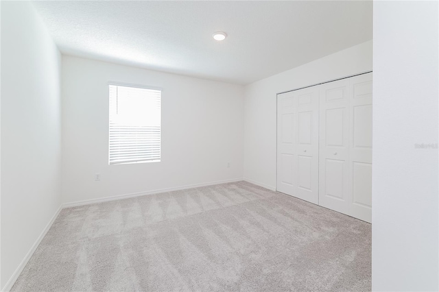 unfurnished bedroom with a closet and light carpet