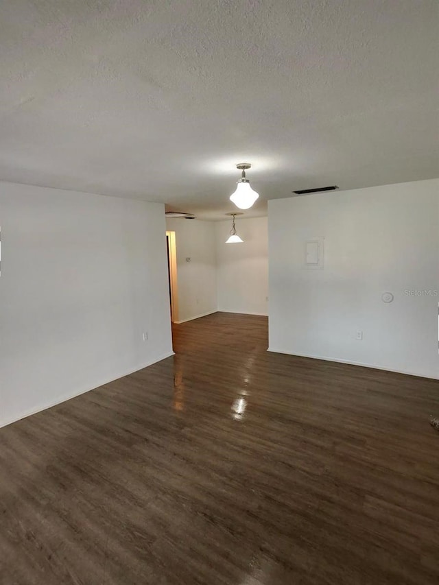 empty room featuring a textured ceiling and dark hardwood / wood-style flooring