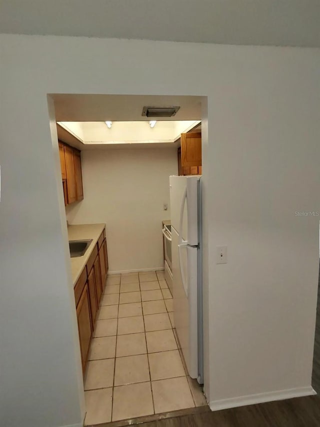 kitchen with sink, light tile patterned flooring, and white appliances