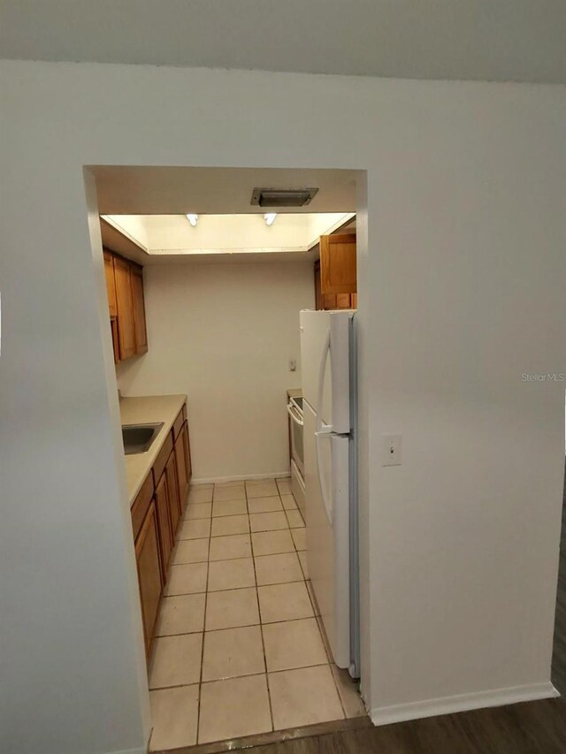 6008 Village Cir Unit Ge, Orlando, FL 32822 - kitchen with freestanding refrigerator, brown cabinets, light countertops, and electric range