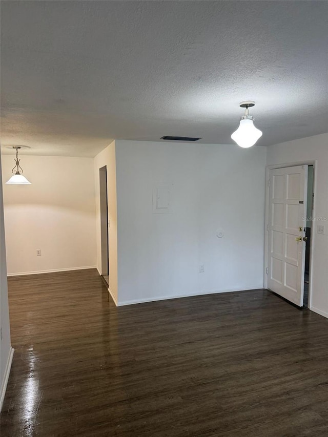 empty room featuring a textured ceiling and dark hardwood / wood-style flooring