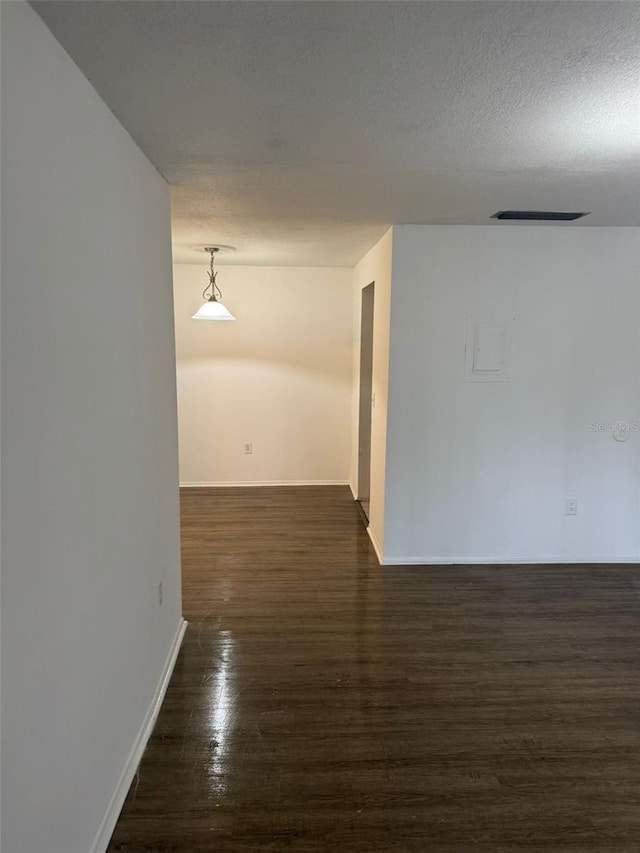 unfurnished room with a textured ceiling and dark hardwood / wood-style floors