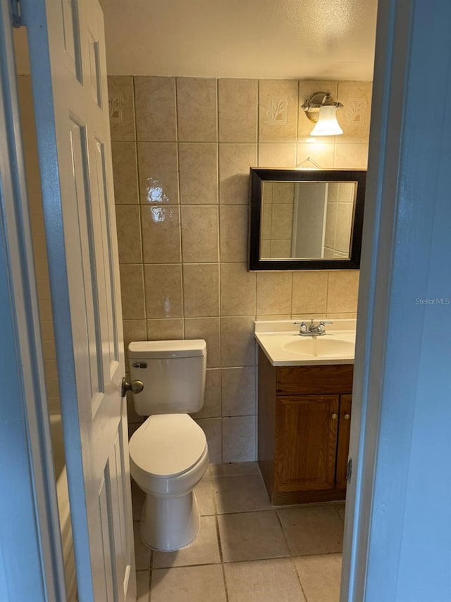 bathroom featuring vanity, toilet, tile walls, and tile patterned flooring