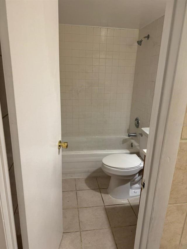 bathroom with toilet, tiled shower / bath, and tile patterned floors