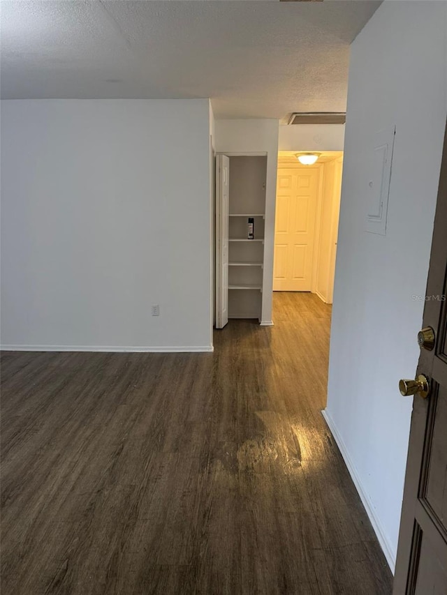 empty room featuring dark wood-type flooring and a textured ceiling