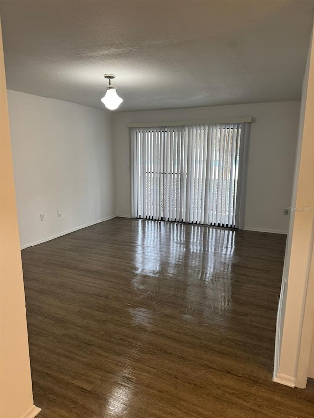 unfurnished room featuring plenty of natural light, a textured ceiling, and dark hardwood / wood-style floors