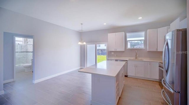 kitchen with pendant lighting, white cabinets, a kitchen island, and appliances with stainless steel finishes