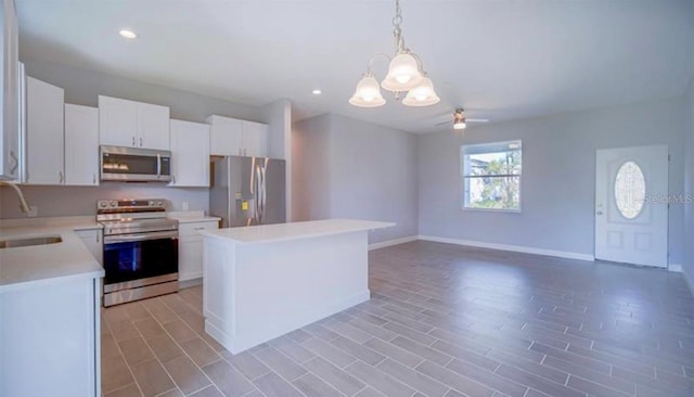 kitchen with light wood-type flooring, appliances with stainless steel finishes, hanging light fixtures, white cabinets, and a center island