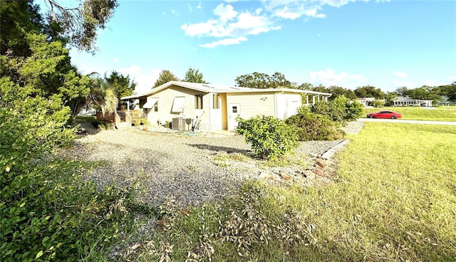 view of side of home featuring central AC unit and a lawn