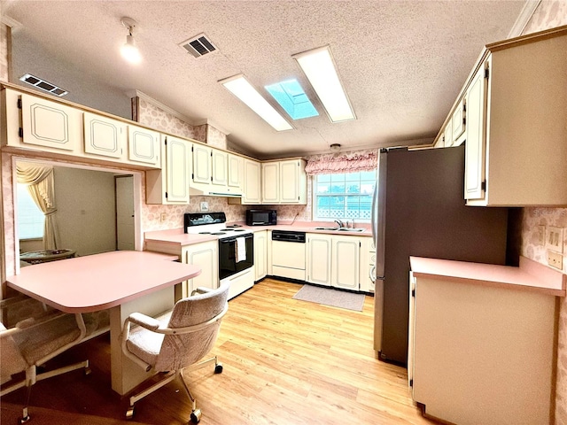 kitchen with light hardwood / wood-style floors, sink, vaulted ceiling with skylight, a textured ceiling, and white appliances