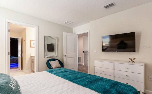 bedroom with a textured ceiling and ensuite bath