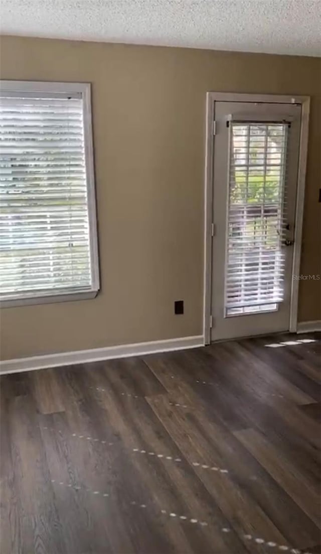 spare room featuring a textured ceiling and dark hardwood / wood-style floors