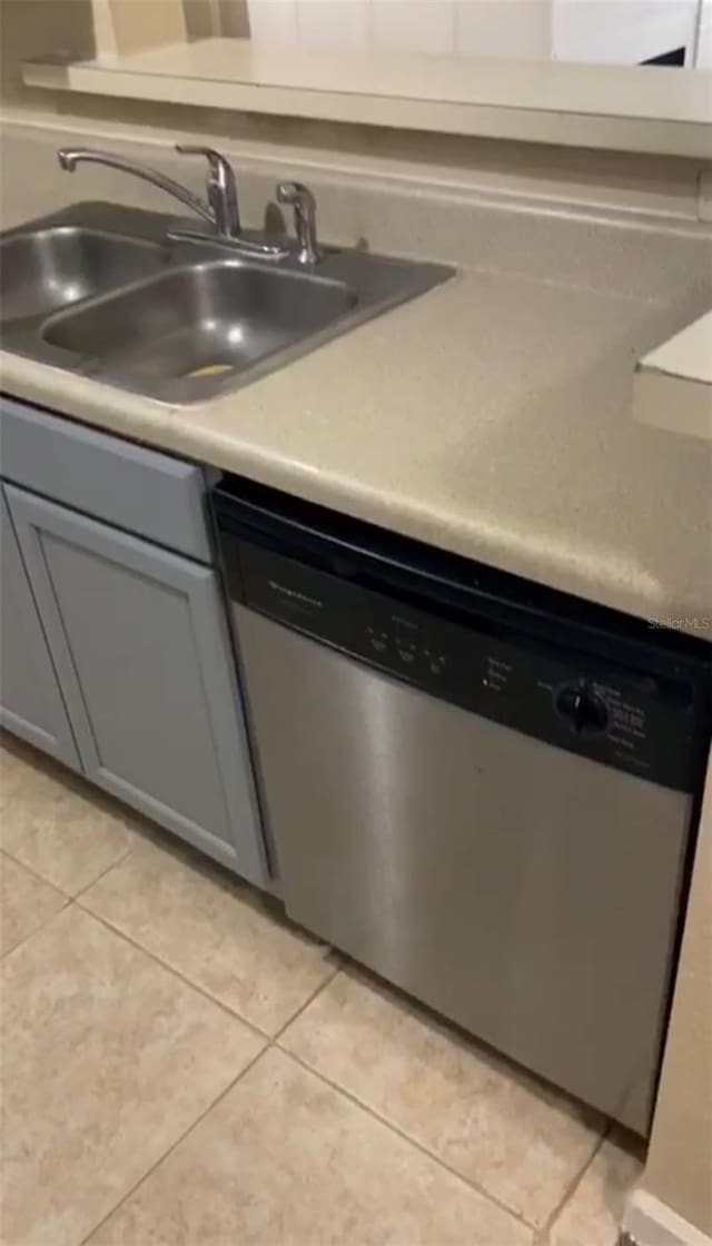 kitchen with dishwasher, gray cabinets, light tile patterned floors, and sink