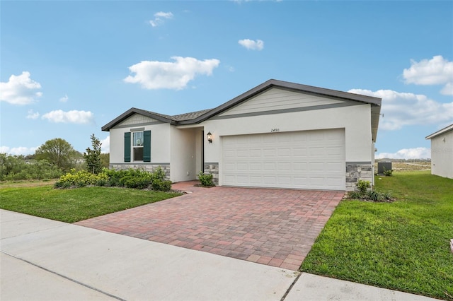 view of front of property featuring stucco siding, decorative driveway, stone siding, an attached garage, and a front yard