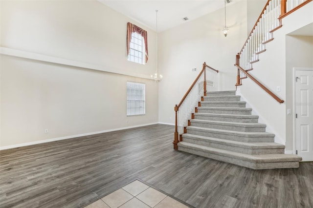 stairway featuring a high ceiling, a wealth of natural light, and hardwood / wood-style flooring