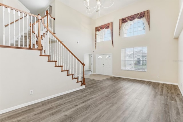 entrance foyer with a towering ceiling, an inviting chandelier, hardwood / wood-style floors, and plenty of natural light